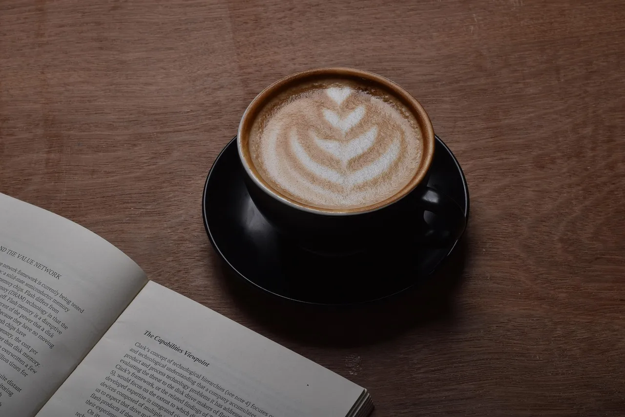 A cappuccino next to an open book